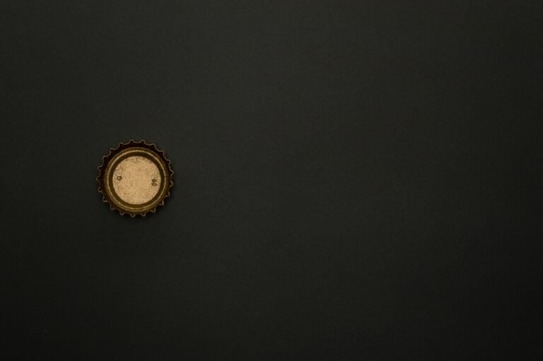 Minimalist image of a golden bottle cap on a dark surface, providing ample copy space.